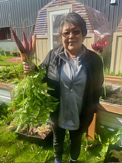 Fairbanks Native Association elder holding carrots from the garden.